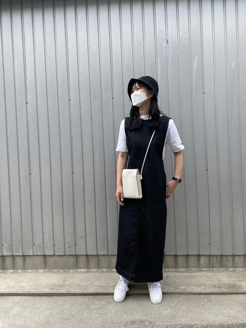 ホワイト系のTシャツ/カットソー、ホワイト系のショルダーバッグ、ブラック系のジャンパースカートを着用したレディースの春コーディネートの3枚目の写真