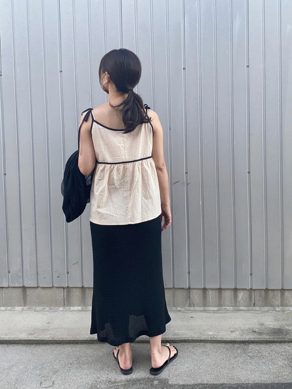 ブラック系のハンドバッグ、ブラック系のスカート、ベージュ系のキャミソールを着用したレディースの夏コーディネートの2枚目の写真