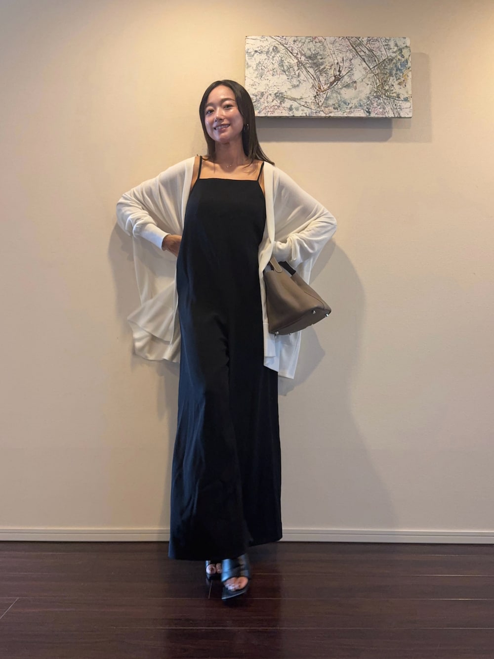 ブラック系のオールインワン・サロペット、ホワイト系のカーディガン/ボレロ、ブラック系のサンダルを着用したレディースの秋コーディネートの2枚目の写真