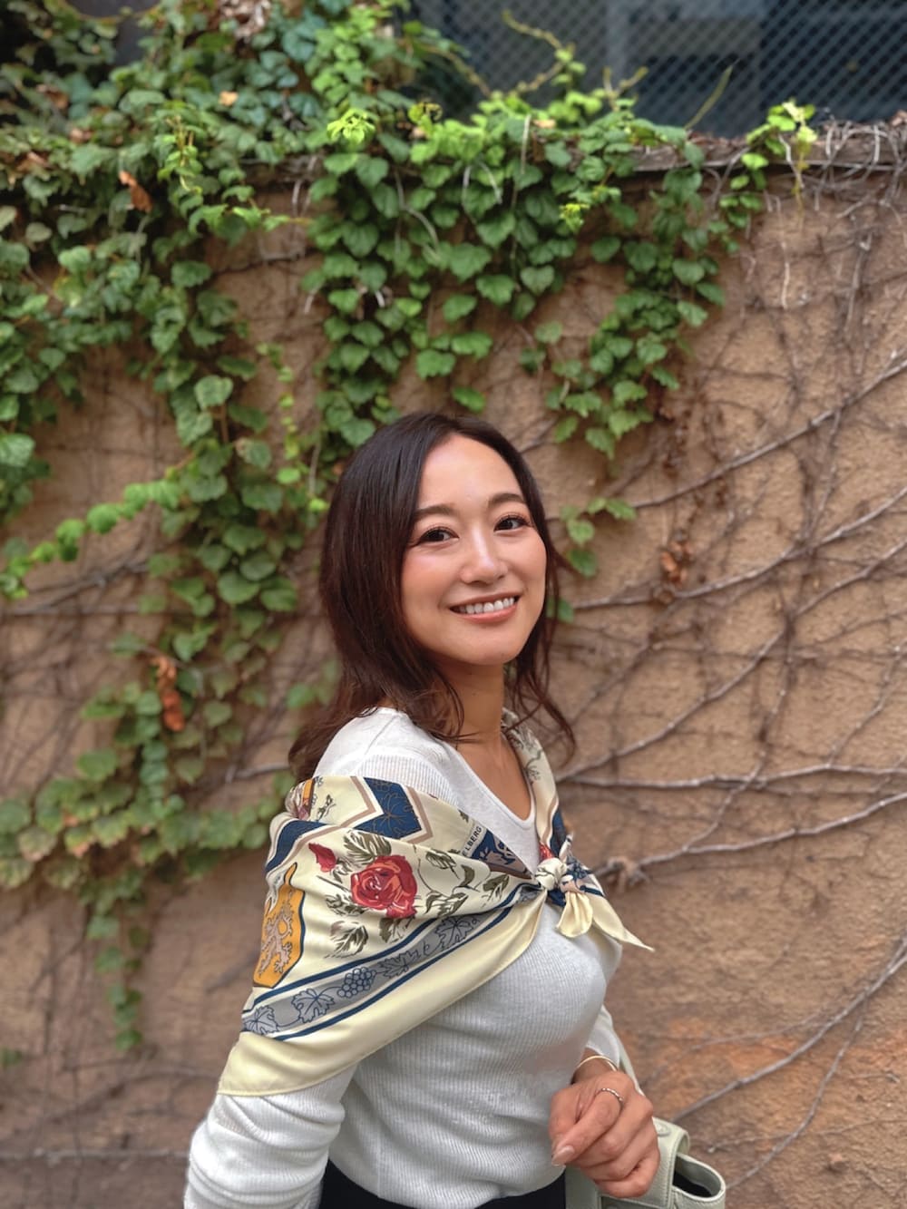 ホワイト系のトップス、ホワイト系のバッグ、ブラック系のスカートを着用したレディースの秋コーディネートの3枚目の写真