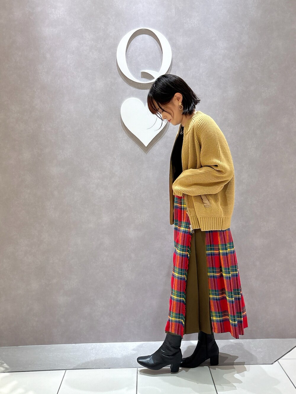 ブラック系のTシャツ/カットソー、ベージュ系のカーディガン/ボレロ、レッド系のスカートを着用したレディースの秋コーディネートの2枚目の写真