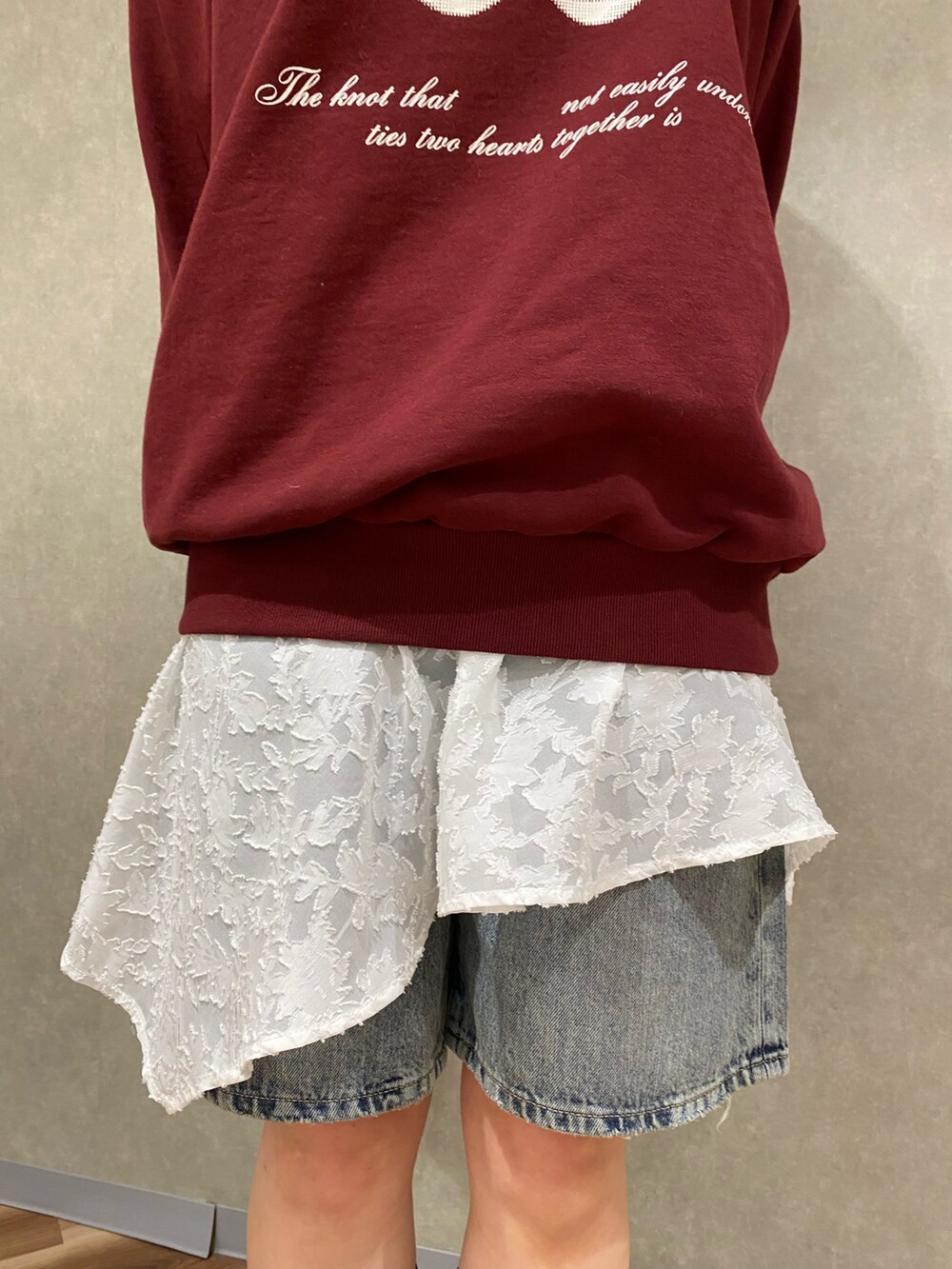 ホワイト系のスカート、ブルー系のデニムパンツ、ブラック系のブーツを着用したレディースの冬コーディネートの6枚目の写真