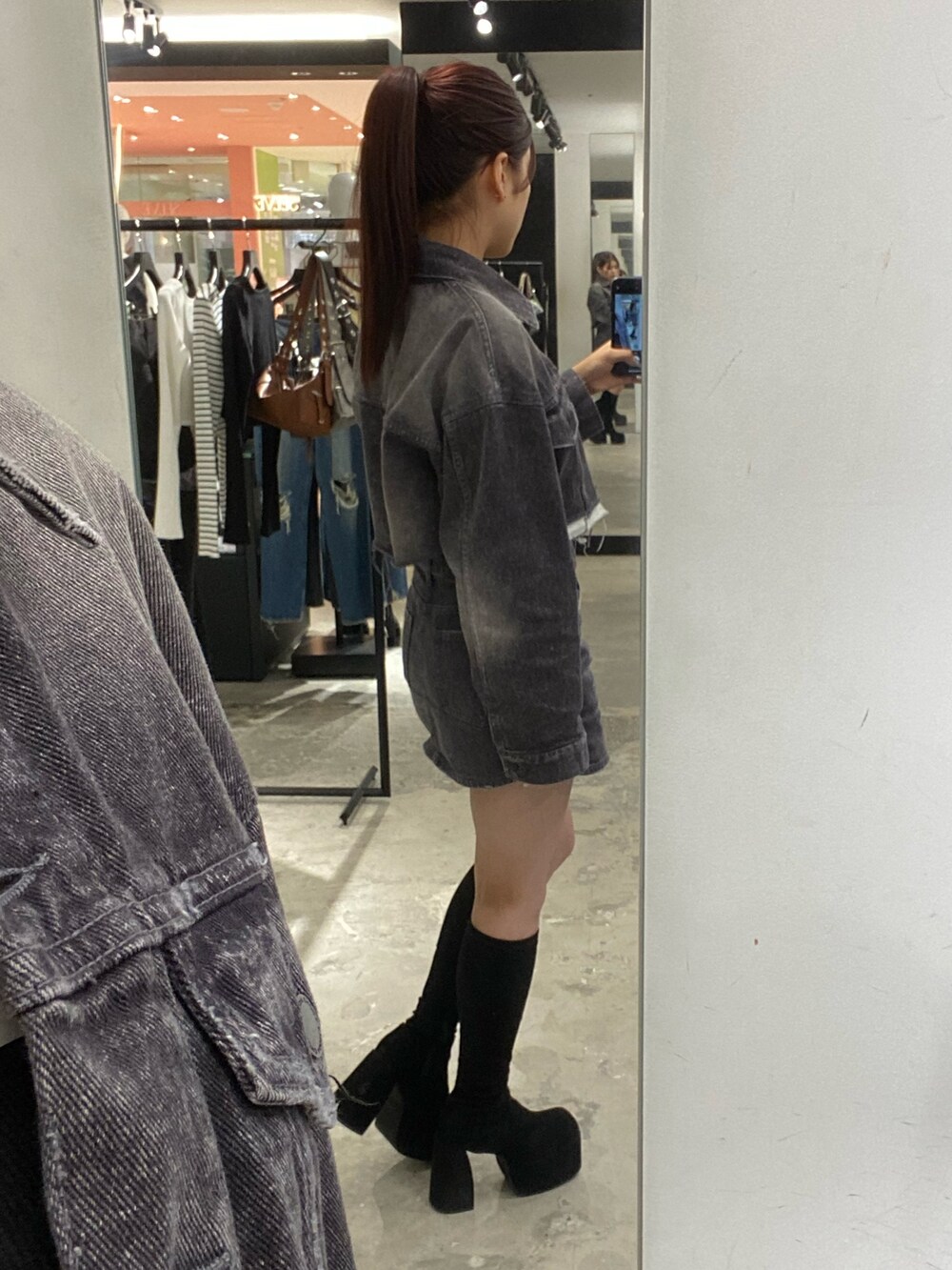 ブラック系のデニムジャケット、ホワイト系のニット/セーター、ブラック系のデニムスカートを着用したレディースの秋コーディネートの8枚目の写真