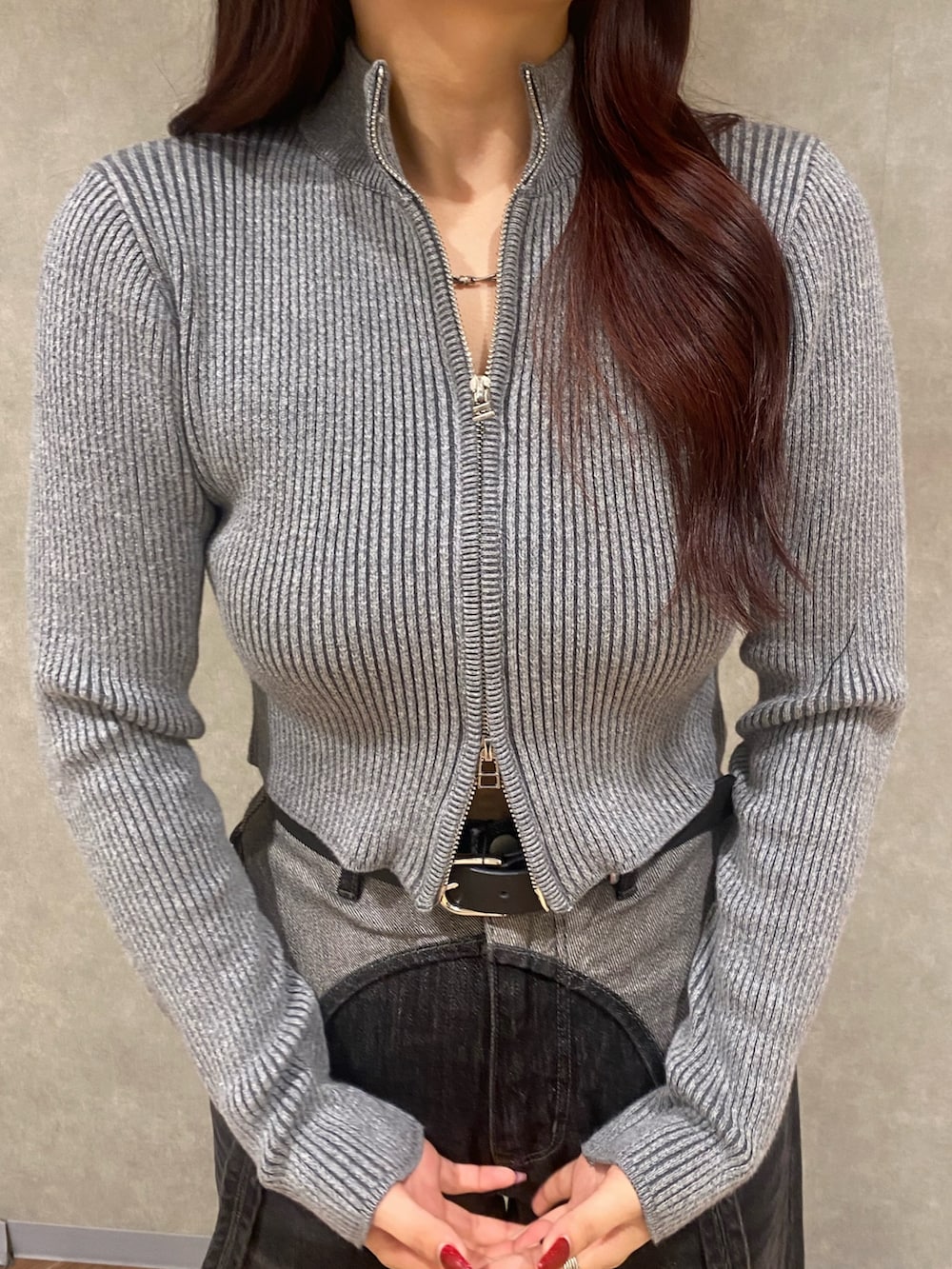 グレー系のニット/セーター、ブラック系のデニムパンツ、ブラック系のブーツを着用したレディースの秋コーディネートの6枚目の写真