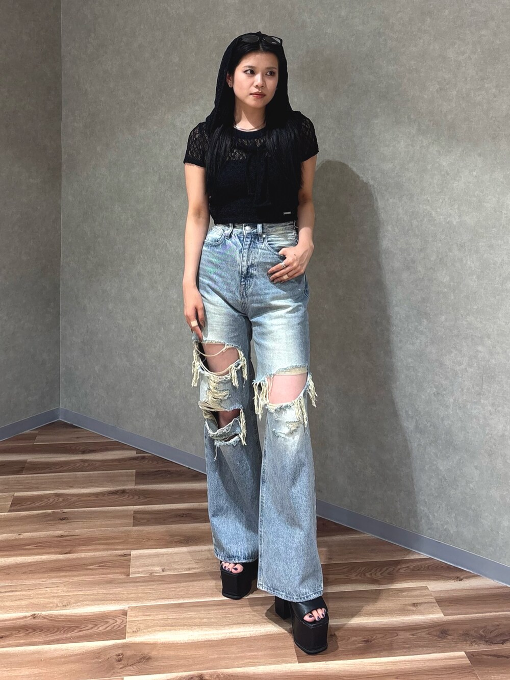 ブルー系のデニムパンツ、ブラック系のサンダル、ブラック系のTシャツ/カットソーを着用したレディースの夏コーディネートの2枚目の写真