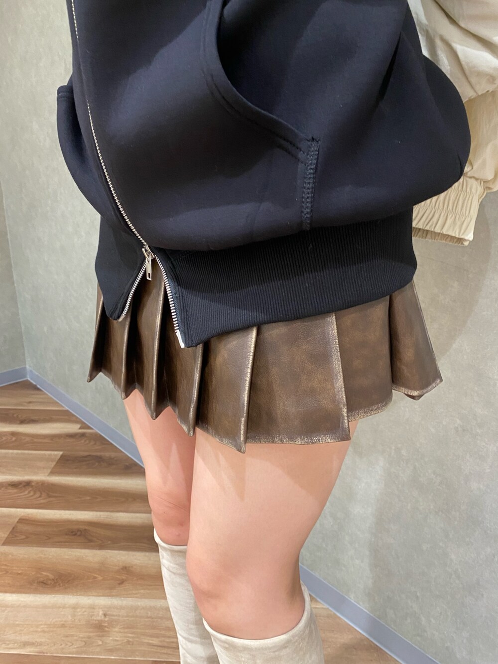 ホワイト系のブルゾン、ブラック系のパーカー、ブラウン系のスカートを着用したレディースの秋コーディネートの6枚目の写真