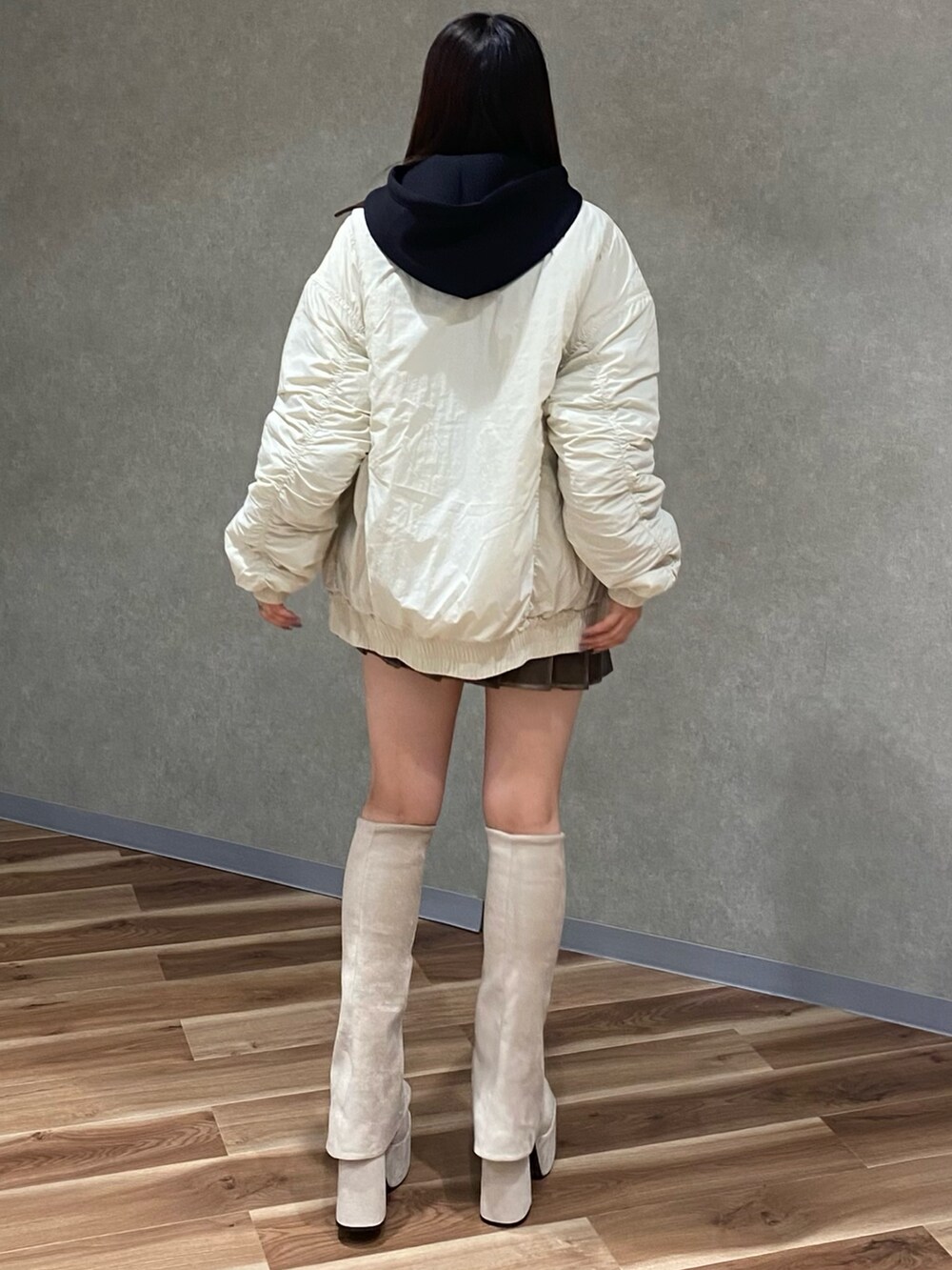 ホワイト系のブルゾン、ブラック系のパーカー、ブラウン系のスカートを着用したレディースの秋コーディネートの4枚目の写真