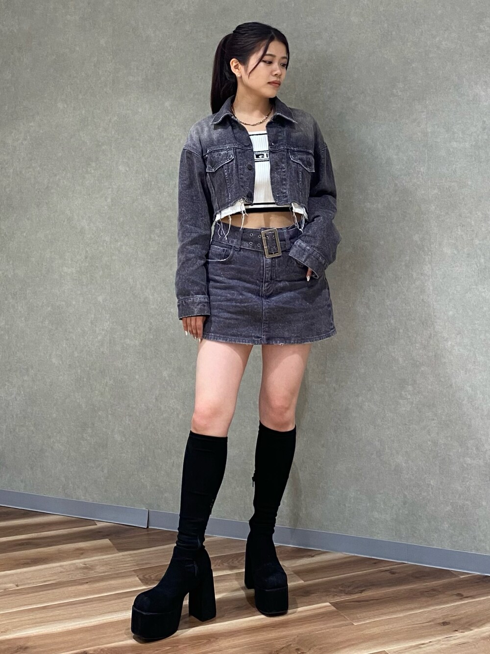 ブラック系のデニムジャケット、ホワイト系のニット/セーター、ブラック系のデニムスカートを着用したレディースの秋コーディネートの2枚目の写真