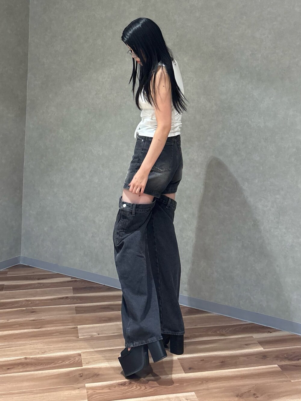 ブラック系のデニムパンツ、ブラック系のサンダル、ホワイト系のTシャツ/カットソーを着用したレディースの夏コーディネートの2枚目の写真