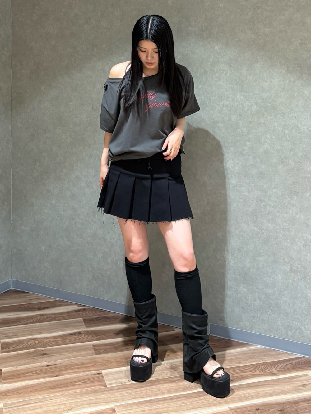 ブラック系のスカート、グレー系のTシャツ/カットソー、ブラック系のサンダルを着用したレディースの春コーディネートの2枚目の写真