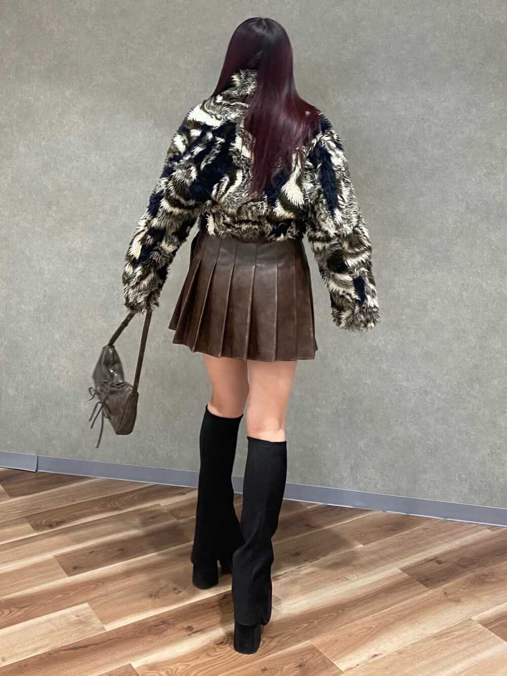 ブラウン系のスカート、ブラウン系のショルダーバッグ、ブラック系のブーツを着用したレディースの秋コーディネートの4枚目の写真