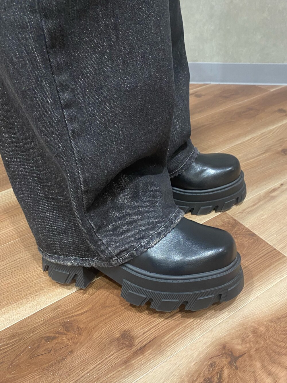 グレー系のニット/セーター、ブラック系のデニムパンツ、ブラック系のブーツを着用したレディースの秋コーディネートの8枚目の写真