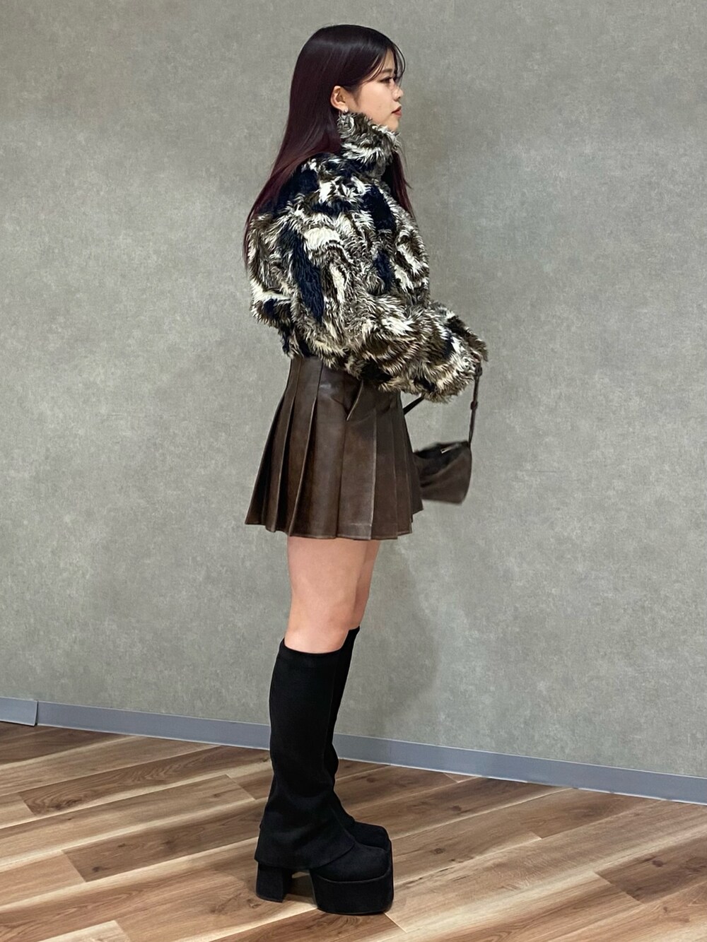 ブラウン系のスカート、ブラウン系のショルダーバッグ、ブラック系のブーツを着用したレディースの秋コーディネートの3枚目の写真