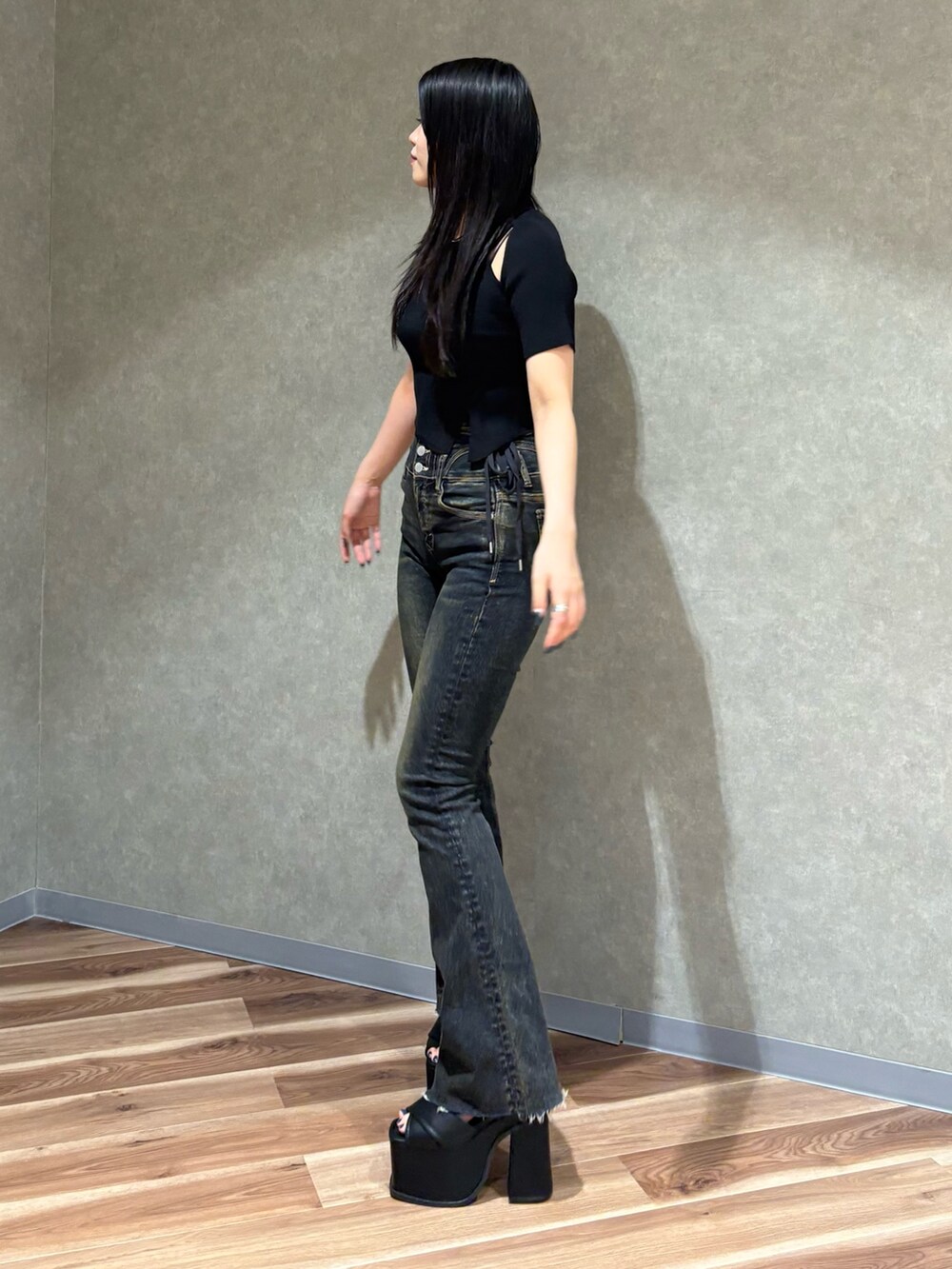 ブラック系のニット/セーター、ブルー系のデニムパンツ、ブラック系のサンダルを着用したレディースの春コーディネートの3枚目の写真