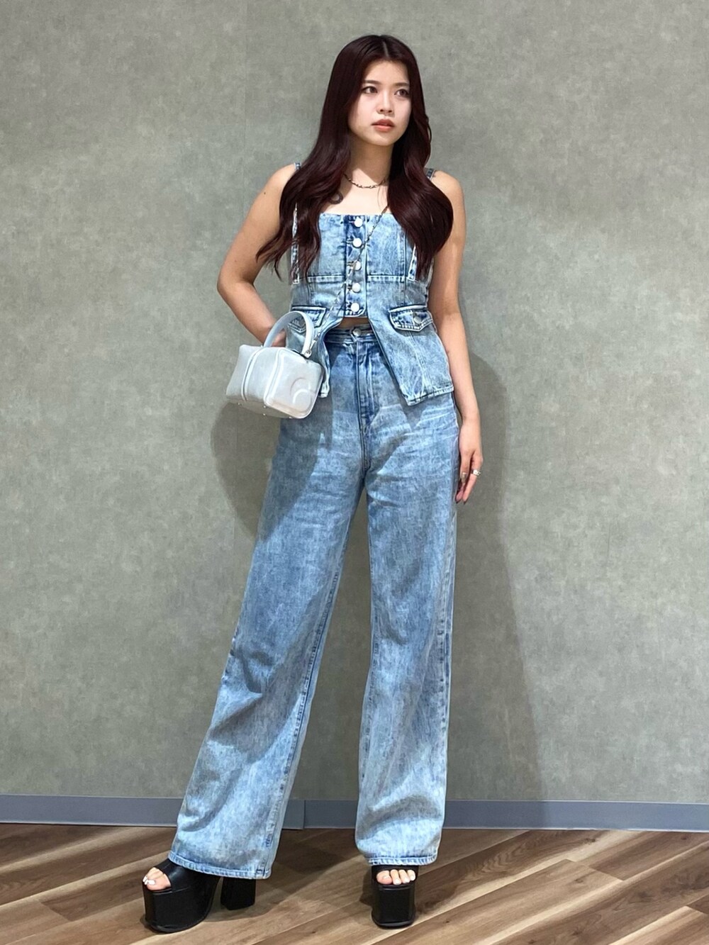 ブルー系のデニムパンツ、ブルー系のキャミソール、シルバー系のハンドバッグを着用したレディースの夏コーディネートの2枚目の写真