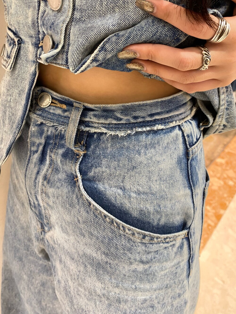 ブルー系のデニムパンツ、ブルー系のキャミソール、シルバー系のハンドバッグを着用したレディースの夏コーディネートの6枚目の写真