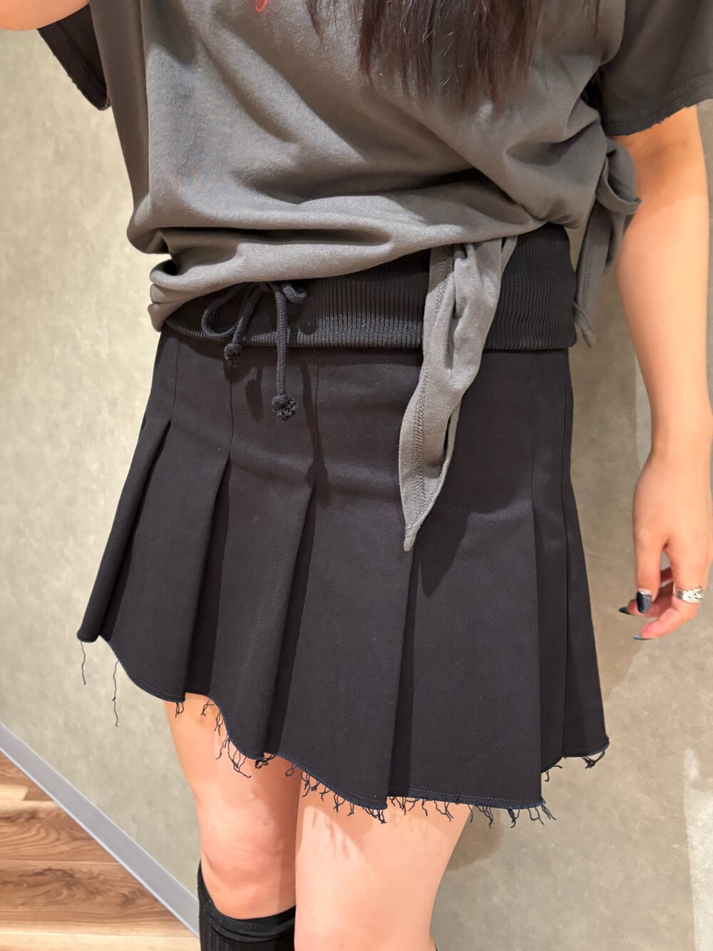 ブラック系のスカート、グレー系のTシャツ/カットソー、ブラック系のサンダルを着用したレディースの春コーディネートの6枚目の写真