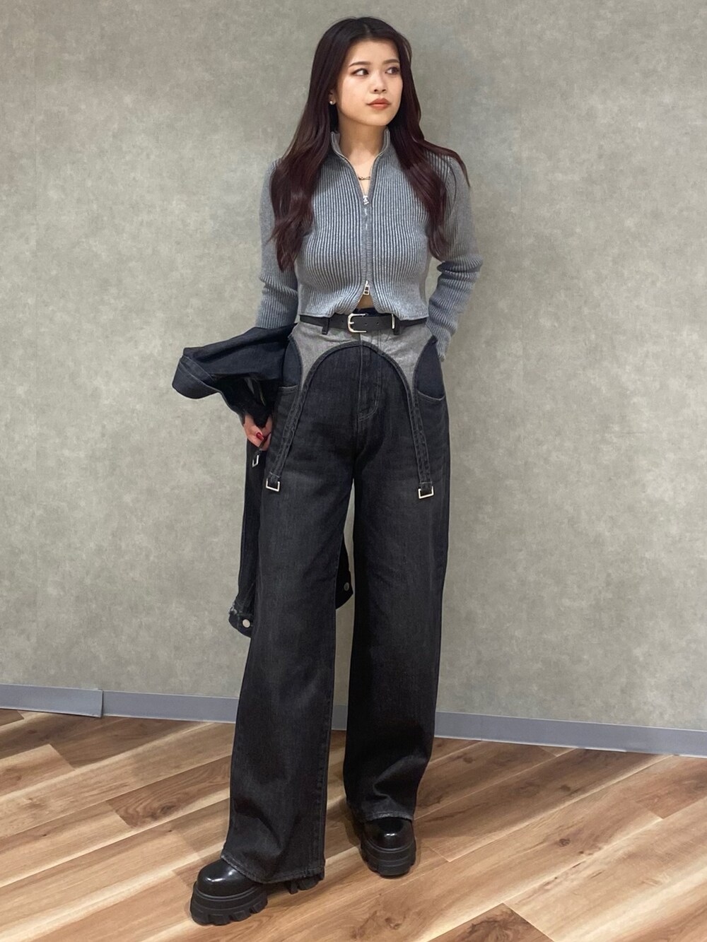 グレー系のニット/セーター、ブラック系のデニムパンツ、ブラック系のブーツを着用したレディースの秋コーディネートの2枚目の写真