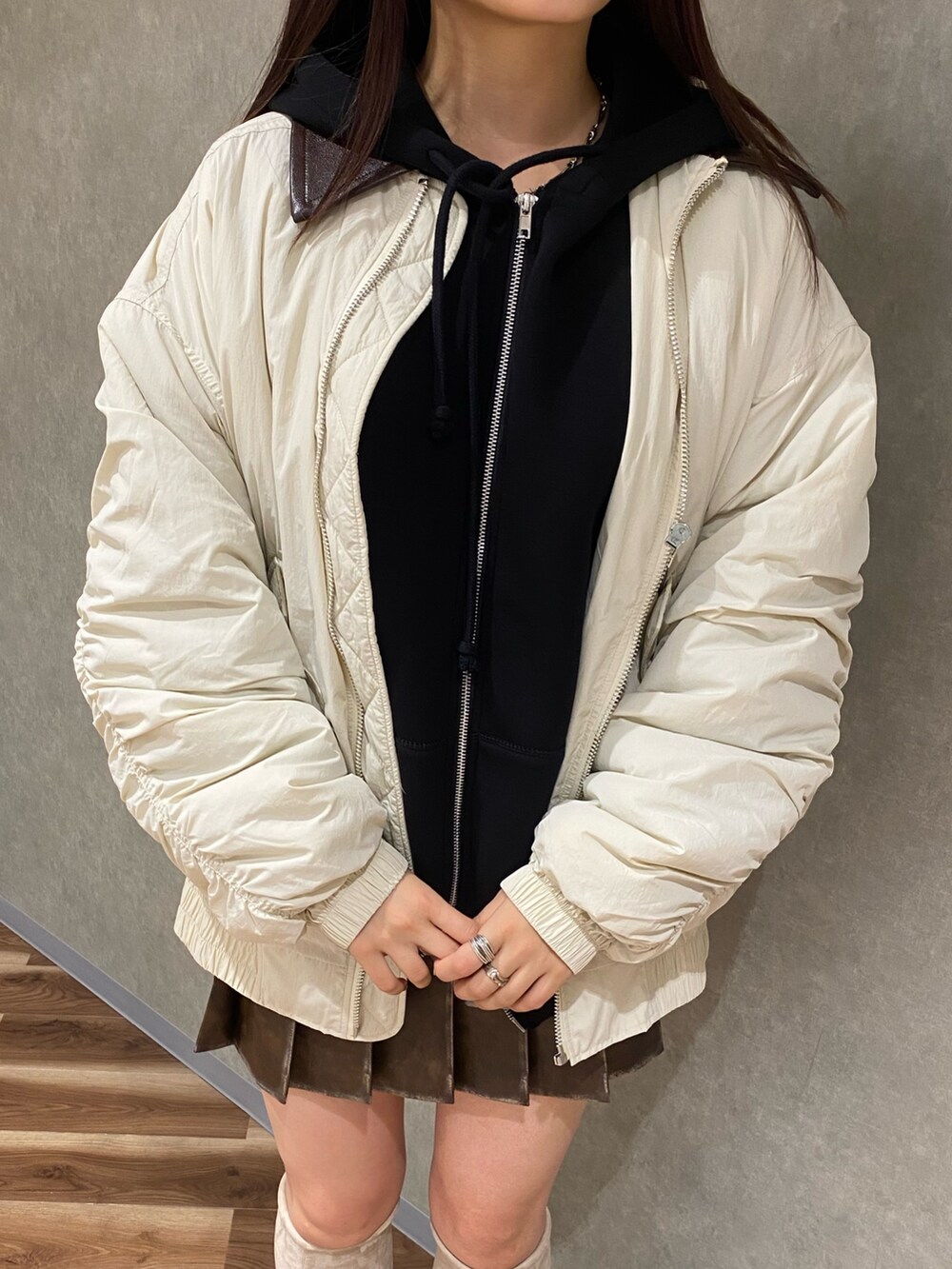 ホワイト系のブルゾン、ブラック系のパーカー、ブラウン系のスカートを着用したレディースの秋コーディネートの5枚目の写真