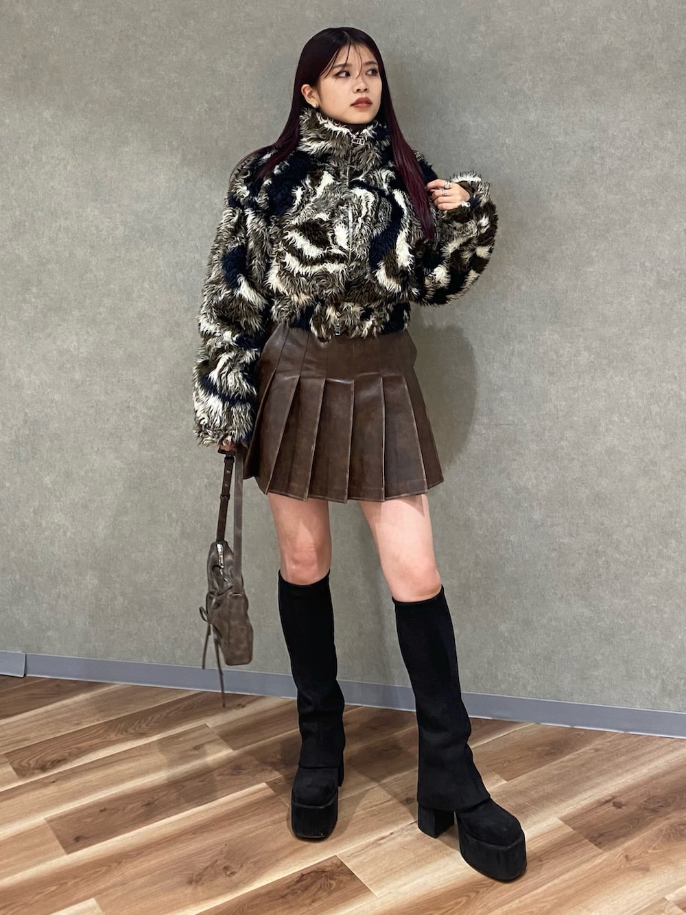 ブラウン系のスカート、ブラウン系のショルダーバッグ、ブラック系のブーツを着用したレディースの秋コーディネートの2枚目の写真