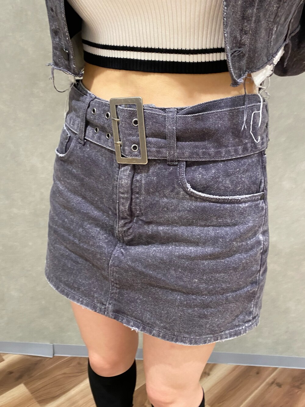 ブラック系のデニムジャケット、ホワイト系のニット/セーター、ブラック系のデニムスカートを着用したレディースの秋コーディネートの6枚目の写真