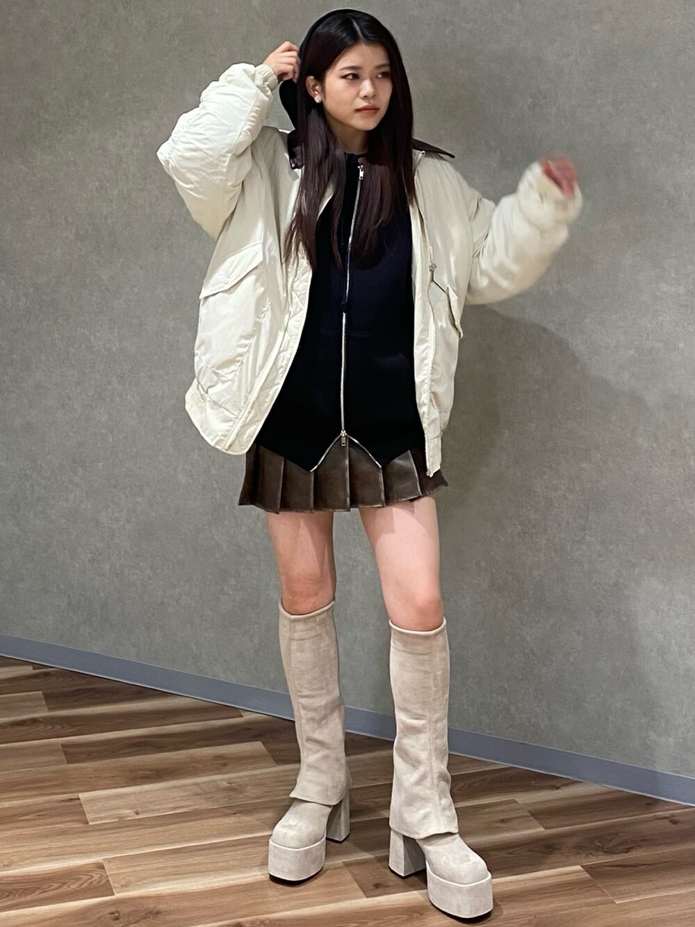 ホワイト系のブルゾン、ブラック系のパーカー、ブラウン系のスカートを着用したレディースの秋コーディネートの2枚目の写真