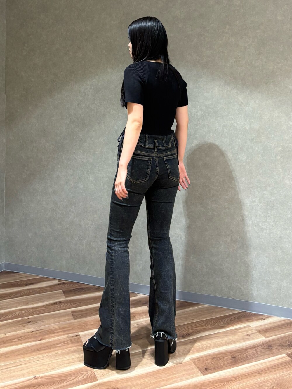 ブラック系のニット/セーター、ブルー系のデニムパンツ、ブラック系のサンダルを着用したレディースの春コーディネートの4枚目の写真