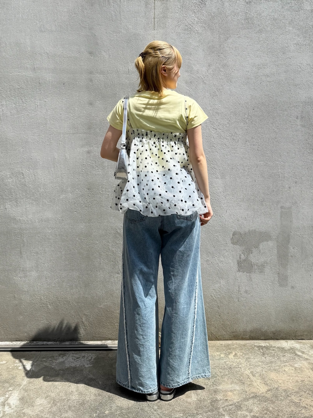 ブルー系のデニムパンツ、シルバー系のブーツ、シルバー系のトートバッグを着用したレディースの春コーディネートの3枚目の写真