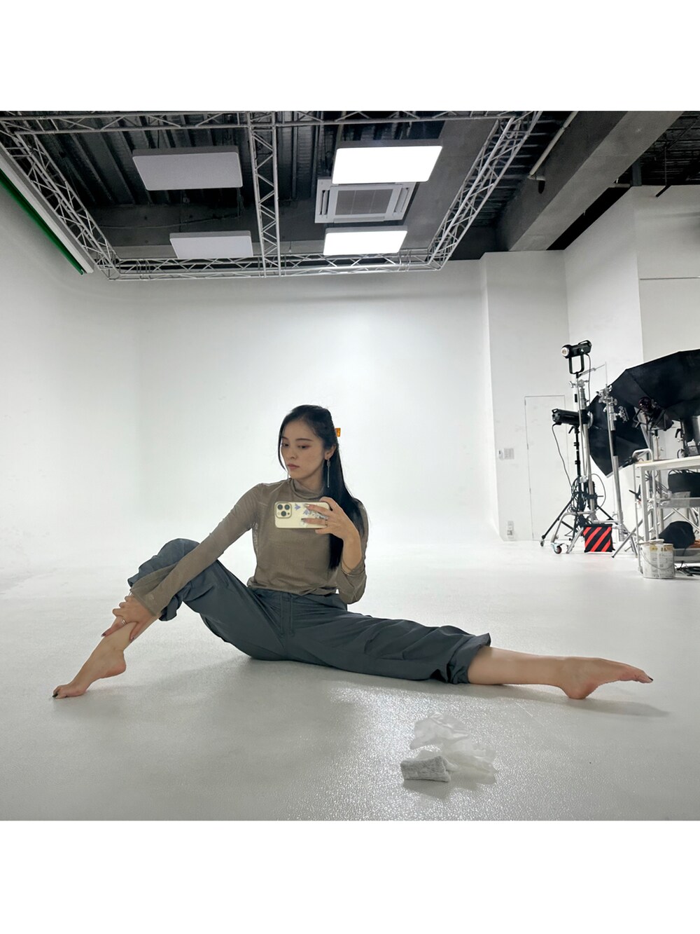 グレー系のパンツ、ベージュ系のトップス、グリーン系のバッグを着用したレディースの秋コーディネートの2枚目の写真