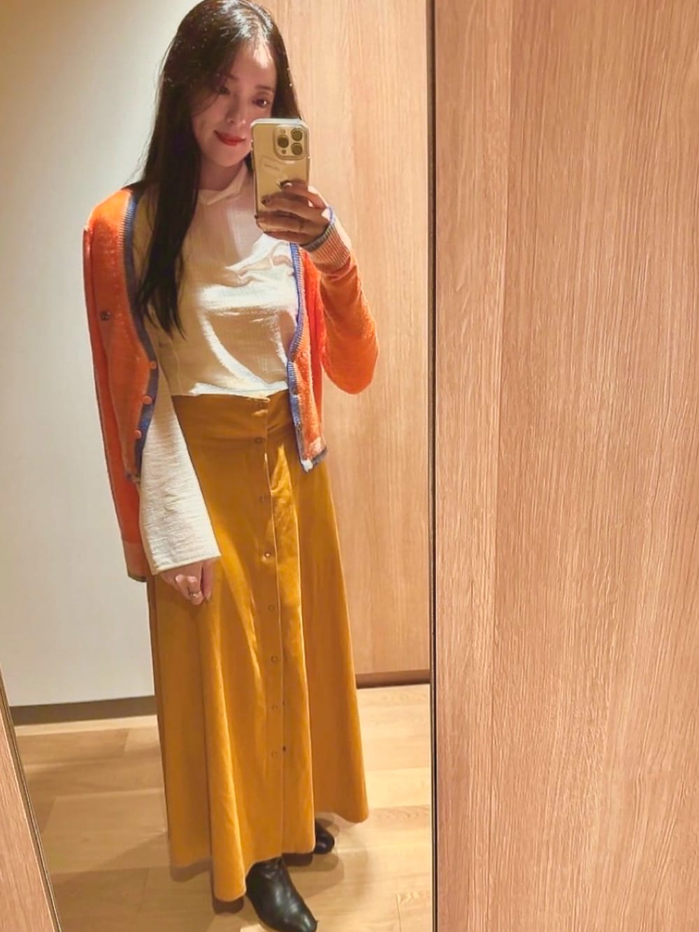 イエロー系のスカート、ブルー系のカーディガン/ボレロ、ホワイト系のトップスを着用したレディースの秋コーディネートの2枚目の写真