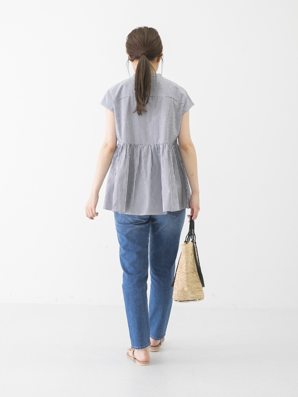 ベージュ系のショルダーバッグ、ブルー系のデニムパンツ、グレー系のシャツ/ブラウスを着用したレディースの春コーディネートの3枚目の写真