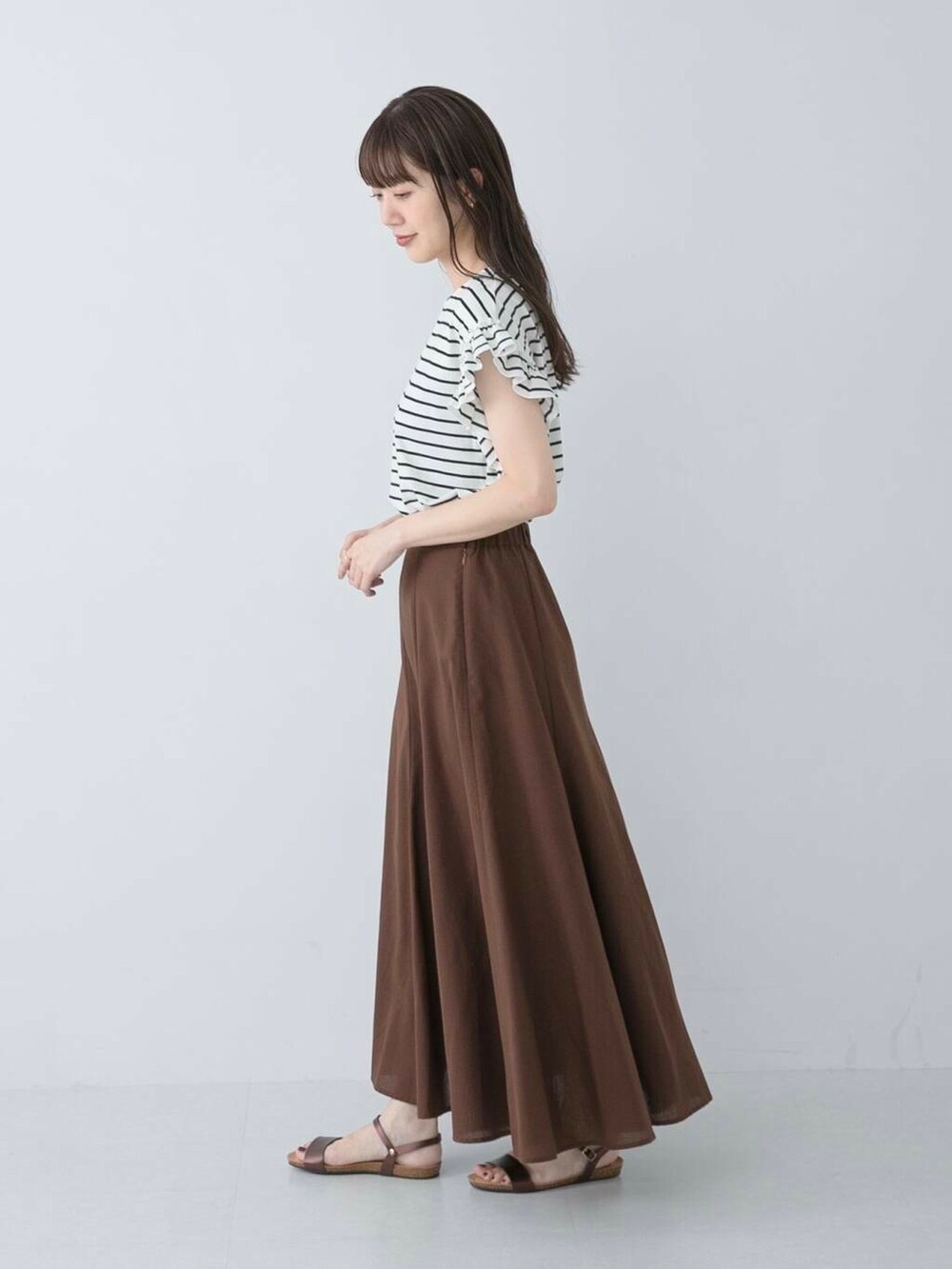 ブラウン系のサンダル、ブラック系のTシャツ/カットソー、ブラウン系のスカートを着用したレディースの夏コーディネートの3枚目の写真