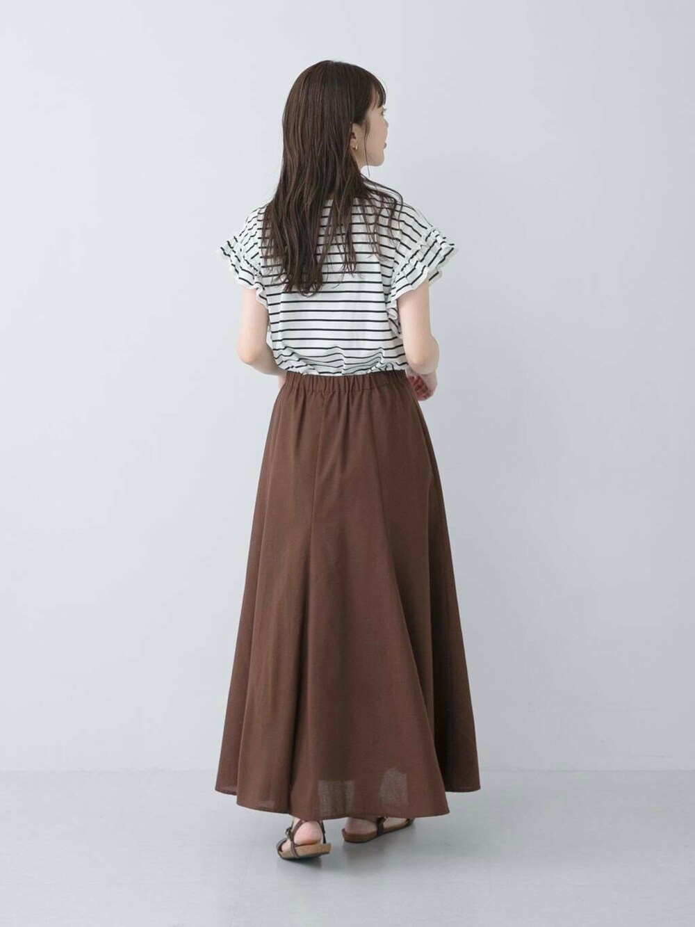 ブラウン系のサンダル、ブラック系のTシャツ/カットソー、ブラウン系のスカートを着用したレディースの夏コーディネートの2枚目の写真