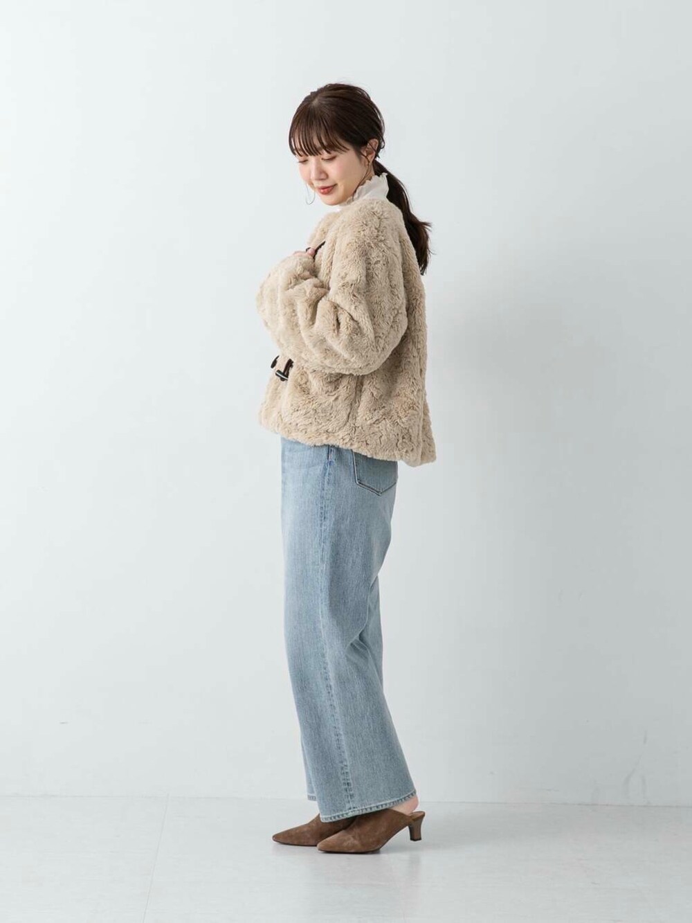 ブルー系のデニムパンツ、ブラウン系のその他シューズ、ホワイト系のその他アウターを着用したレディースの冬コーディネートの4枚目の写真