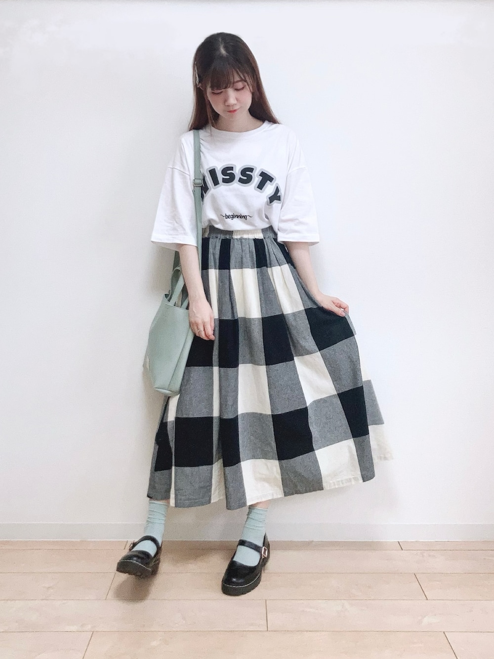 ホワイト系のTシャツ/カットソー、ブラック系のスカート、グリーン系のショルダーバッグを着用したレディースの夏コーディネートの3枚目の写真