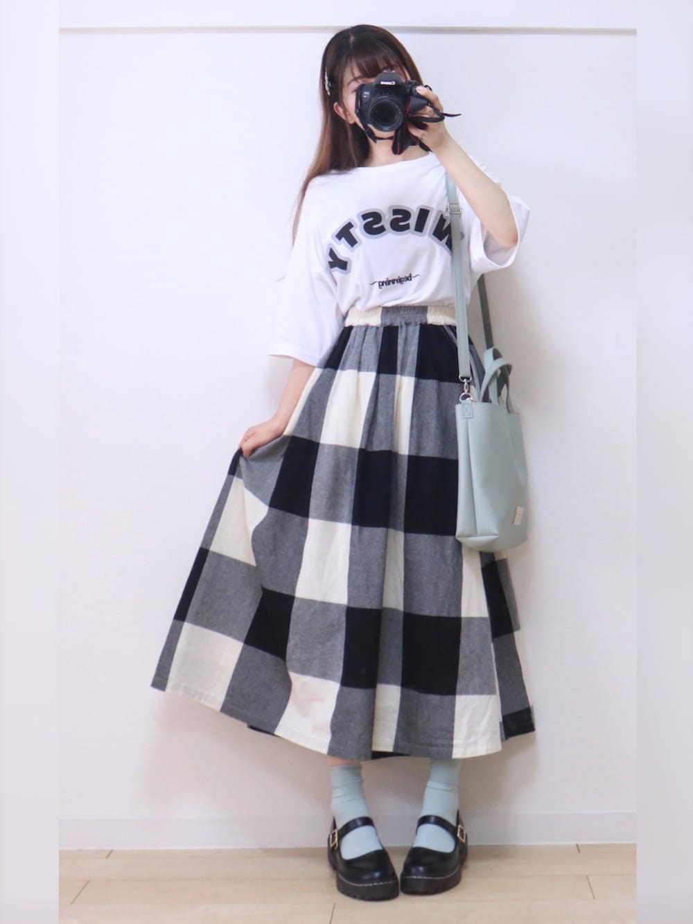 ホワイト系のTシャツ/カットソー、ブラック系のスカート、グリーン系のショルダーバッグを着用したレディースの夏コーディネートの4枚目の写真