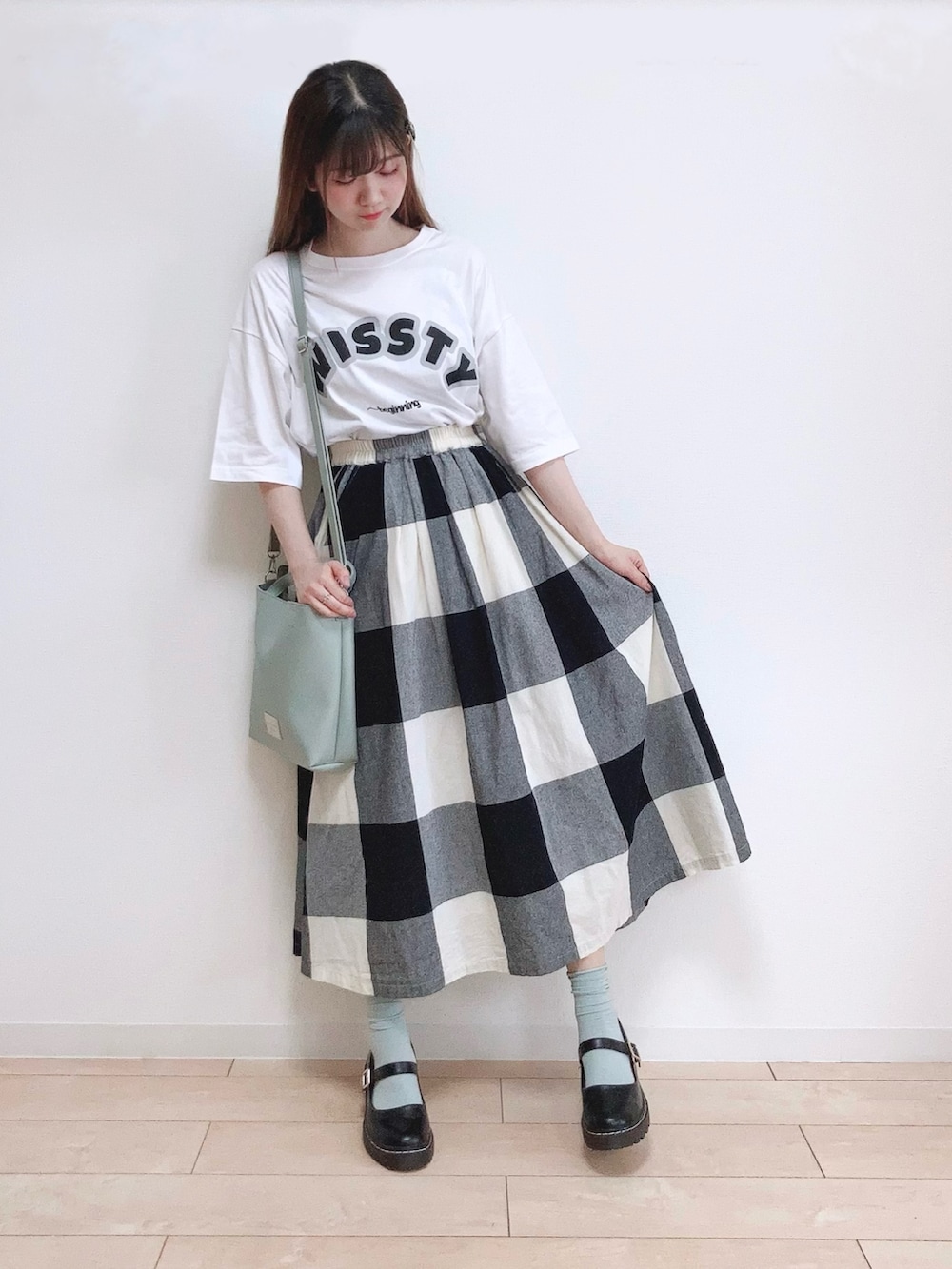 ホワイト系のTシャツ/カットソー、ブラック系のスカート、グリーン系のショルダーバッグを着用したレディースの夏コーディネートの2枚目の写真