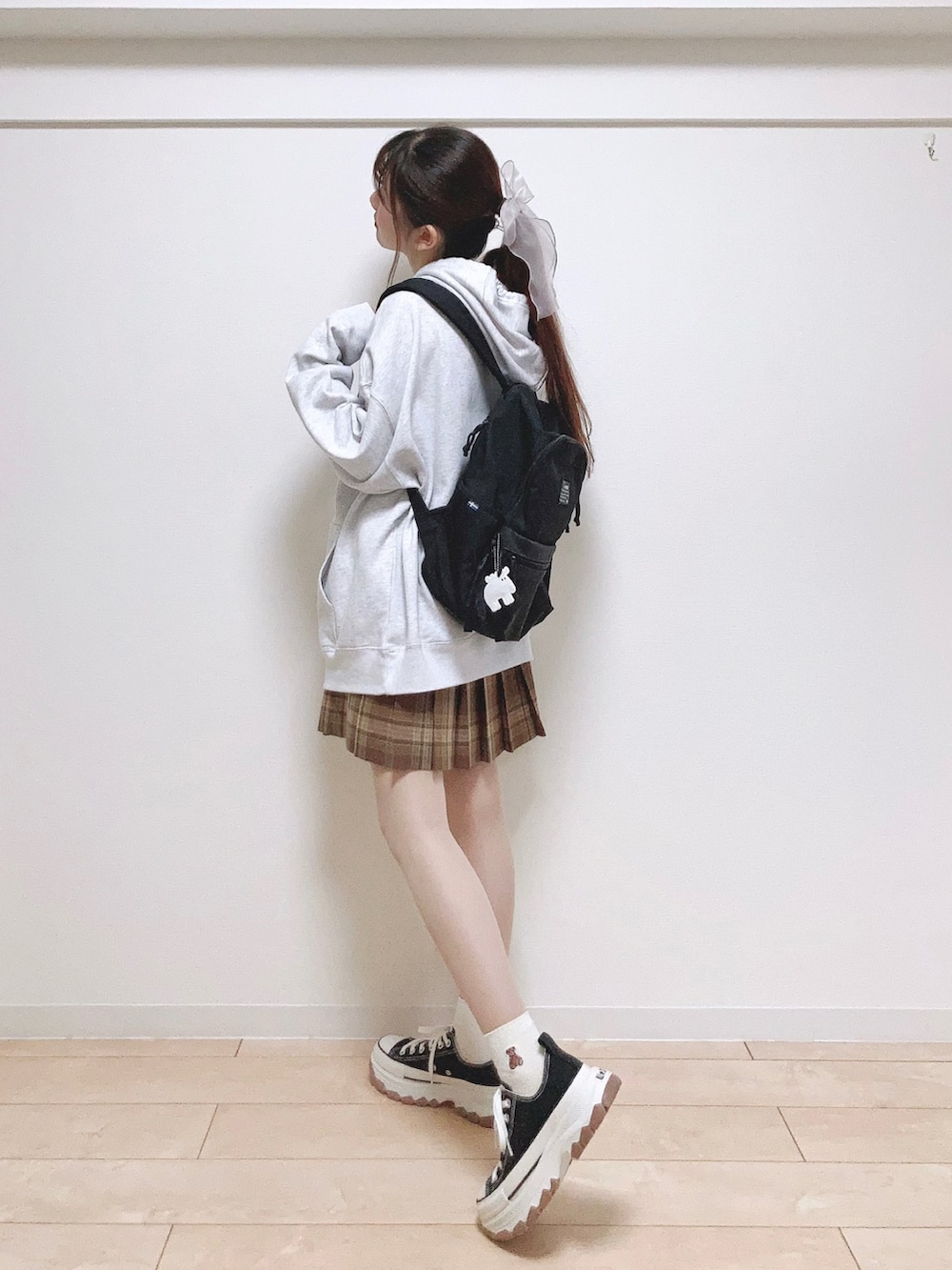 グレー系のスウェット、ブラック系のバックパック/リュック、ブラウン系のスカートを着用したレディースの秋コーディネートの4枚目の写真