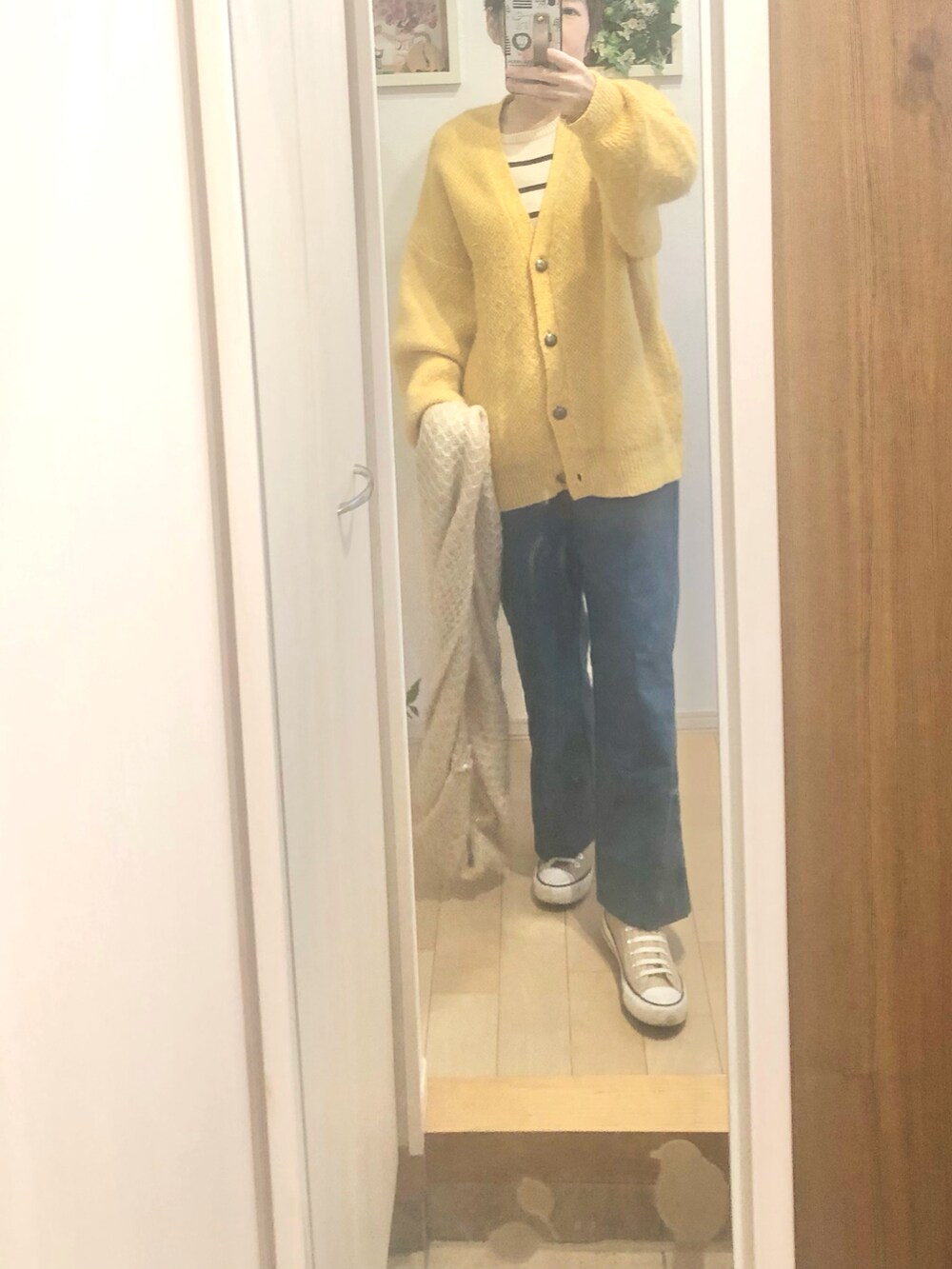 イエロー系のカーディガン/ボレロ、ベージュ系のスニーカー、ブルー系のその他パンツを着用したレディースの冬コーディネートの2枚目の写真