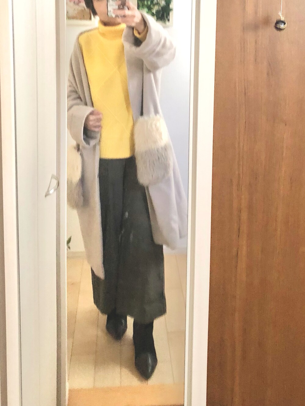 イエロー系のニット/セーター、グリーン系のパンツ、ブラック系のブーツを着用したレディースの冬コーディネートの2枚目の写真