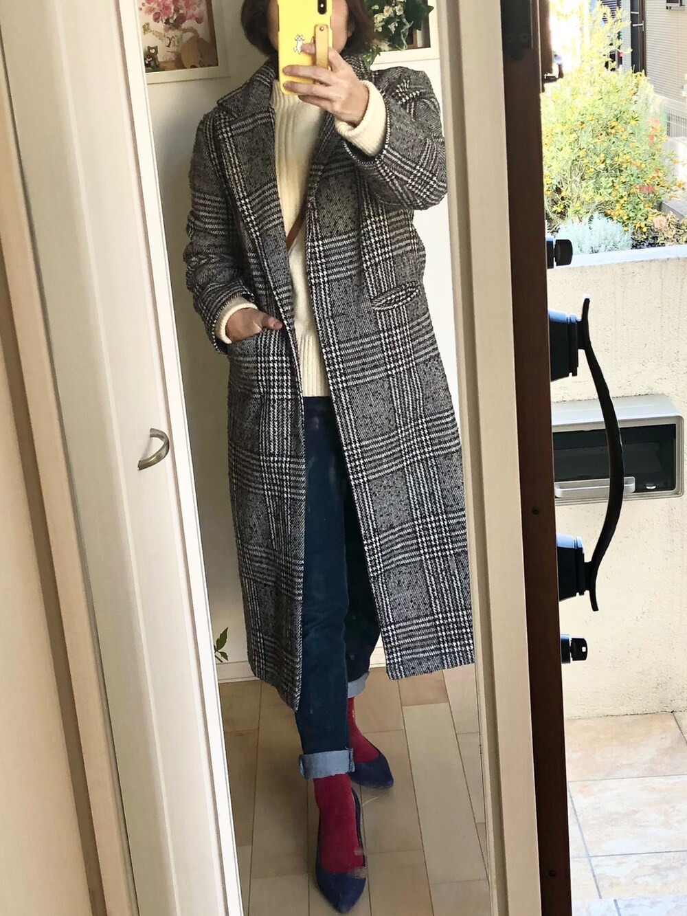 ホワイト系のニット/セーター、ブルー系のデニムパンツ、ブラウン系のチェスターコートを着用したレディースの冬コーディネートの2枚目の写真