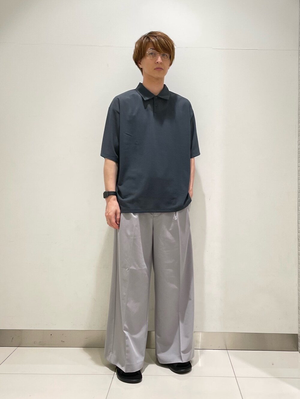 ブルー系のポロシャツ、ブラック系のショルダーバッグ、グレー系のスラックスを着用したメンズの夏コーディネートの3枚目の写真