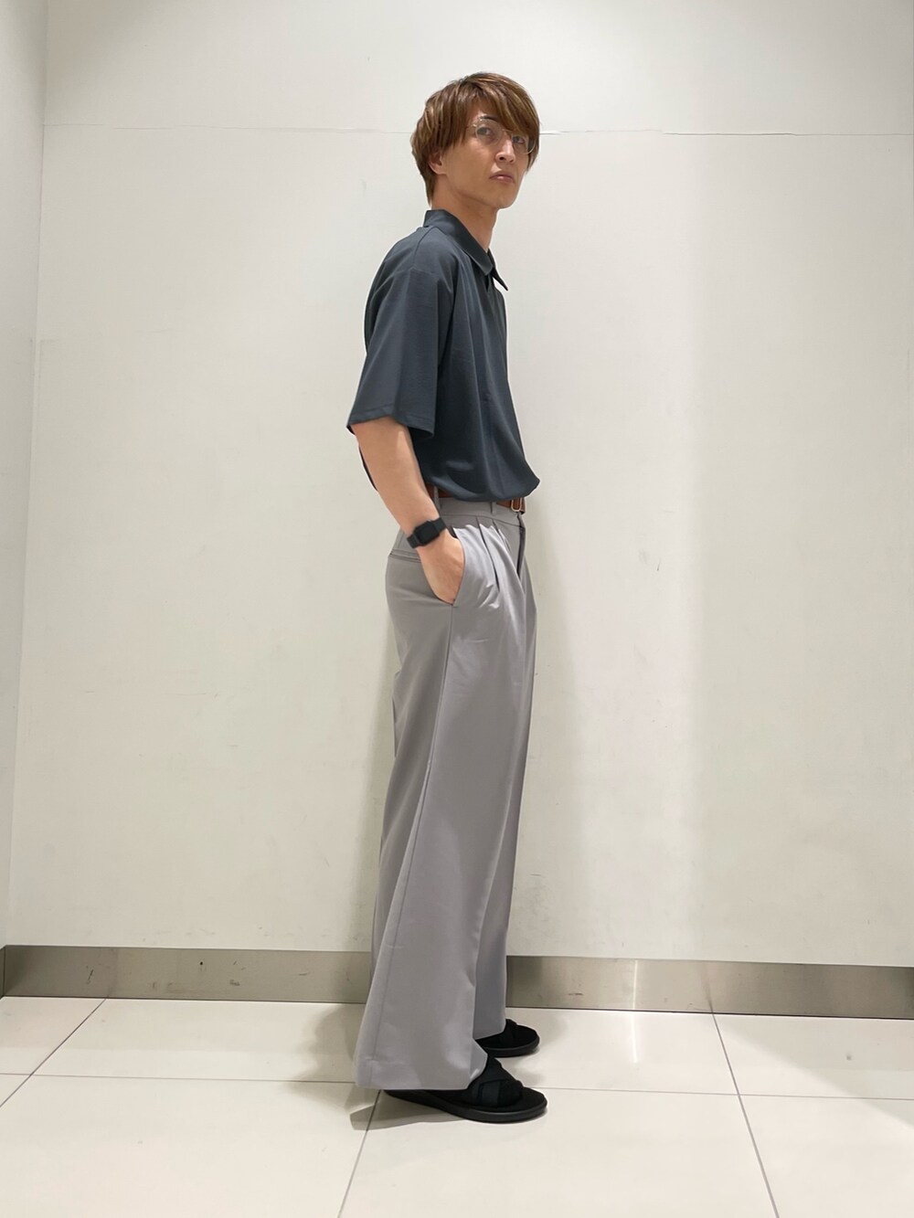 ブルー系のポロシャツ、ブラック系のショルダーバッグ、グレー系のスラックスを着用したメンズの夏コーディネートの2枚目の写真