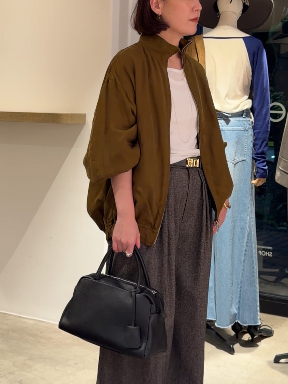 グリーン系のブルゾン、ホワイト系のTシャツ/カットソー、ベージュ系のスラックスを着用したレディースの秋コーディネートの3枚目の写真