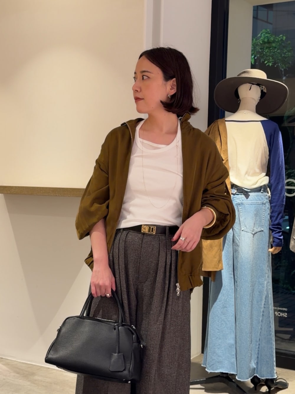 グリーン系のブルゾン、ホワイト系のTシャツ/カットソー、ベージュ系のスラックスを着用したレディースの秋コーディネートの4枚目の写真