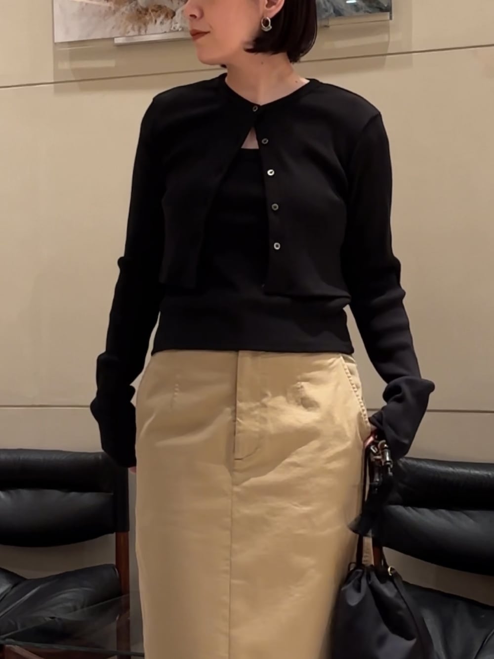 ブラック系のTシャツ/カットソー、ブラック系のカーディガン/ボレロ、ベージュ系のスカートを着用したレディースの春コーディネートの2枚目の写真