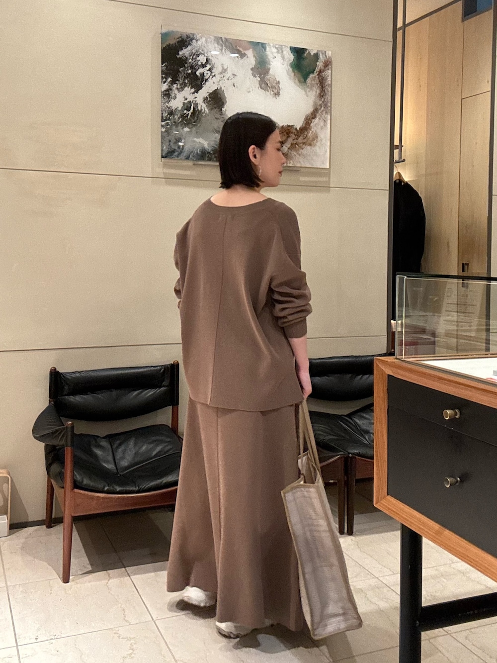 ベージュ系のニット/セーター、ベージュ系のスカート、ベージュ系のトートバッグを着用したレディースの冬コーディネートの2枚目の写真