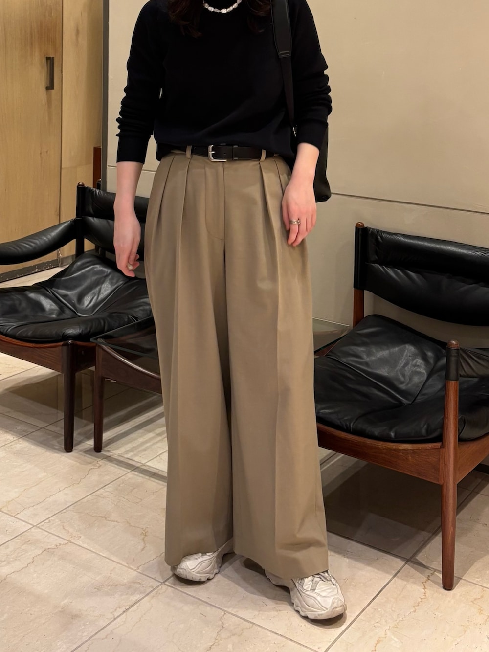 ブラック系のニット/セーター、ベージュ系のその他パンツ、ブラック系のバックパック/リュックを着用したレディースの春コーディネートの2枚目の写真