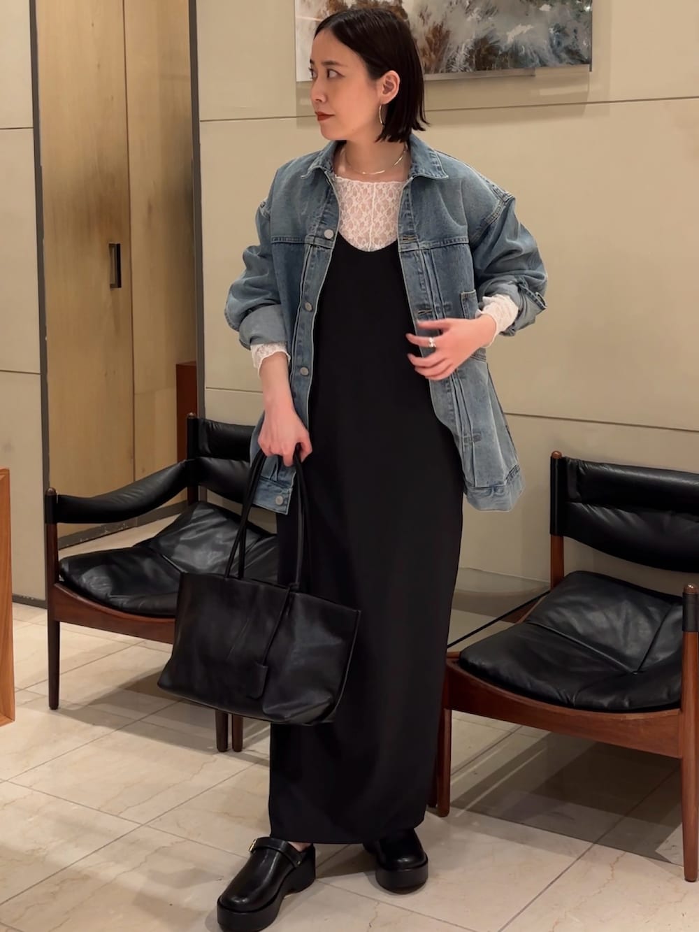 ブラック系のワンピース、ブラック系のブーツ、ブラック系のトートバッグを着用したレディースの春コーディネートの2枚目の写真