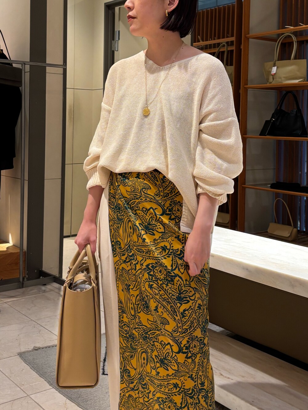 ホワイト系のニット/セーター、ホワイト系のその他パンツ、ベージュ系のトートバッグを着用したレディースの春コーディネートの2枚目の写真